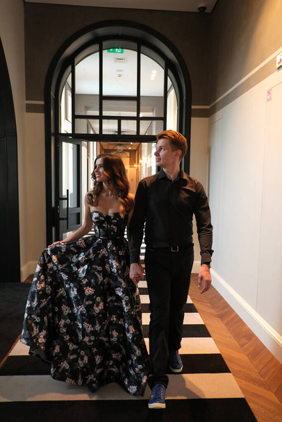 beautiful couple-a girl in a magnificent dress and a guy in a black shirt and trousers are in a building with a beautiful interior - Фото, зображення