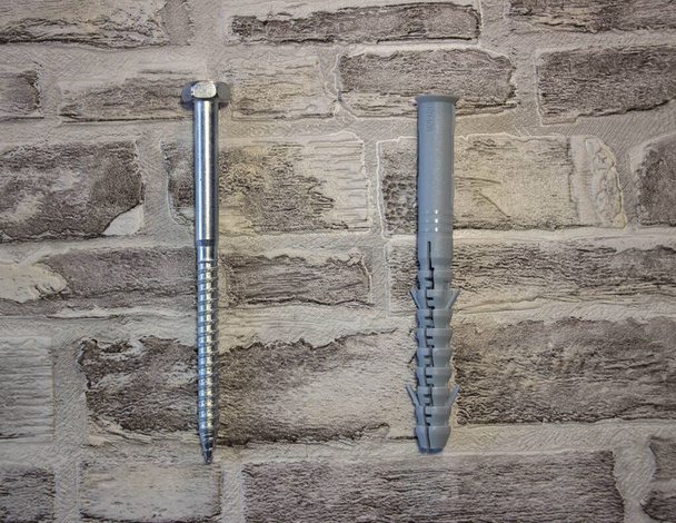 Tapón de anclaje con tornillo de llave universal contra un wal de ladrillo
 - Foto, imagen