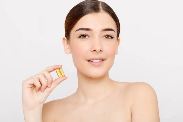 Healthy diet food. Beautiful smiling young woman holding a fish oil pill in her hand. Closeup. taking capsule. Vitamin and dietary supplements - Foto, immagini