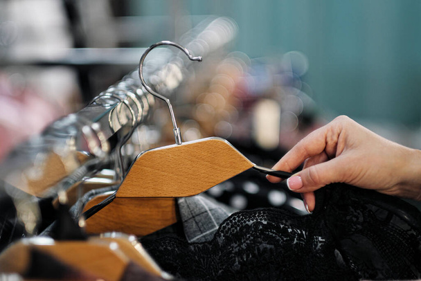 Close-up of the hands of a woman choosing clothes on a hanger in a store. - Foto, Bild