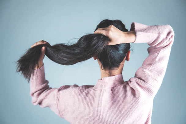 mulher amarrar o cabelo no fundo cinza
 - Foto, Imagem
