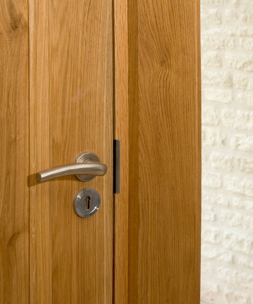 Manija de puerta contemporánea en una puerta interior cerrada de madera maciza
 - Foto, imagen