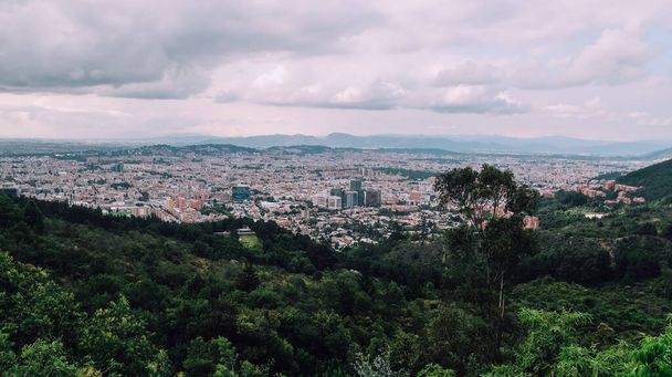 BOGOTA, COLOMBIA - CIRCA NOVEMBER 2019: vanuit de lucht uitzicht op Bogota en de bergen met bewolkte lucht. - Foto, afbeelding