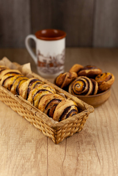Round homemade cookies on the table. Striped cookies with cocoa and cinnamon. Appetizing rolls for a cup of coffee for breakfast. Wooden background in place for text. - Foto, immagini