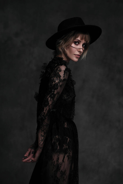 Young beautiful blonde woman in a black hat and dress. - Foto, Imagem