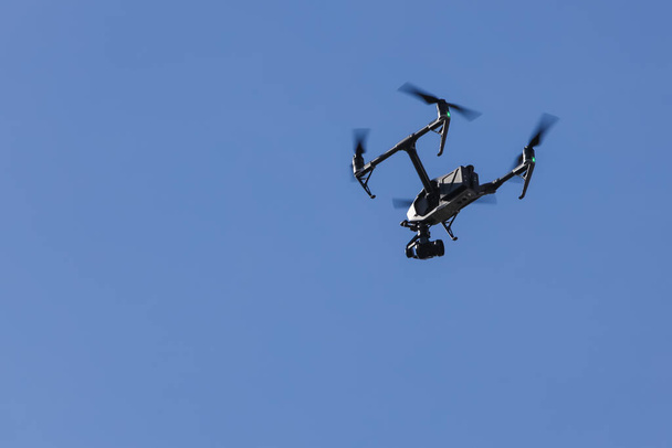 Grande drone para gravação de vídeo voando no ar em um céu azul claro
. - Foto, Imagem