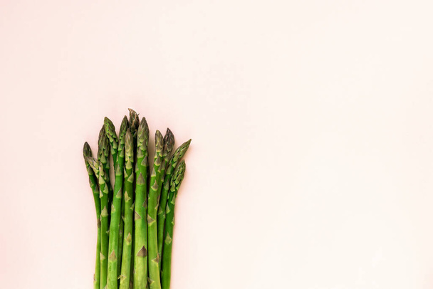 Green fresh asparagus on light cream background. Healthy food concept. Top view, flat lay, copy space. - Fotó, kép