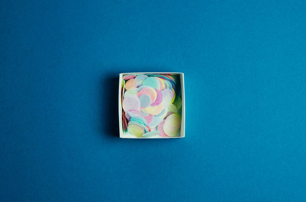 Hermoso fondo festivo con una caja con confeti sobre un fondo azul. La base para el texto o cualquier producto
. - Foto, imagen