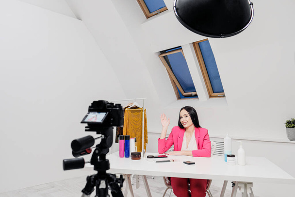 Kadın bir güzellik blogcusu beyaz bir odada video kaydediyor. Bir tripoda ışık ve kamera.. - Fotoğraf, Görsel