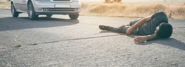 Kaukaski ranny mężczyzna leżący na asfalcie.  - Zdjęcie, obraz