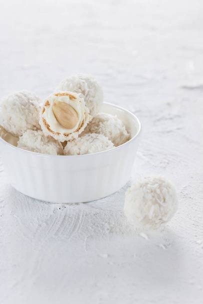 Bonbons au nougat et amandes en flocons de noix de coco sur fond clair
 - Photo, image