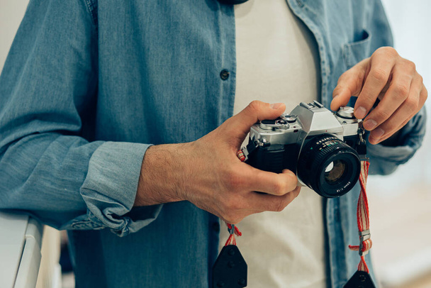Close up of a person in casual clothes holding a stylish camera - Zdjęcie, obraz