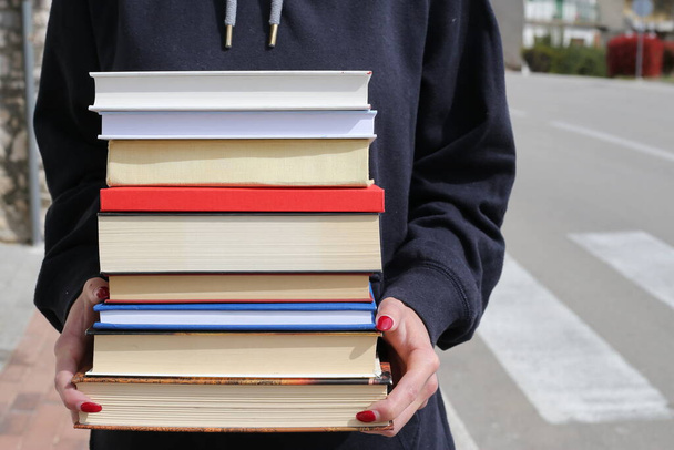 Η μαθήτρια κρατάει βιβλία στα χέρια της. - Φωτογραφία, εικόνα