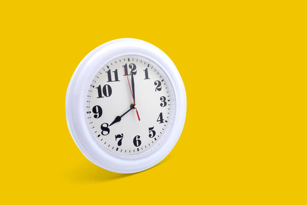 Moderno orologio da parete bianco isolato su sfondo giallo, ora e periodo, orologio da ufficio e mockup con ora e minuto, lancetta delle ore, oggetto classico
. - Foto, immagini