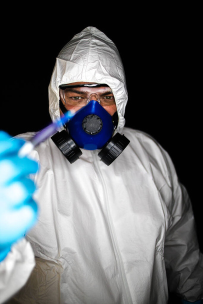 Közelkép egy egészségügyi dolgozóról, aki védőruházatot és maszkot visel, és a veszélyes vírusok elleni vakcinákkal dolgozik. - Fotó, kép