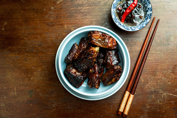 jedzenie aian, karmelizowane żeberka wieprzowe, ciemne drewniane tło, chińskie jedzenie - Zdjęcie, obraz