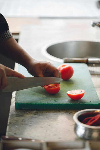 σεφ κόβει ντομάτες στον πίνακα της κουζίνας - Φωτογραφία, εικόνα