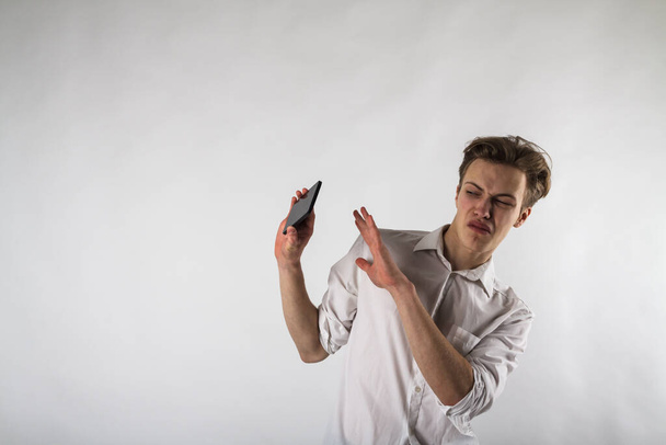 Young man holding smartphone in his hands. Antipathy, dislike and refuse concept. Do not accept false news. - Fotografie, Obrázek