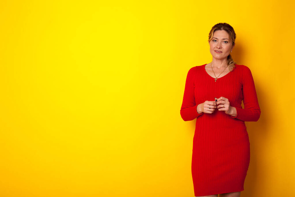 hermosa mujer en vestido rojo sobre un fondo amarillo para inscripciones
 - Foto, imagen