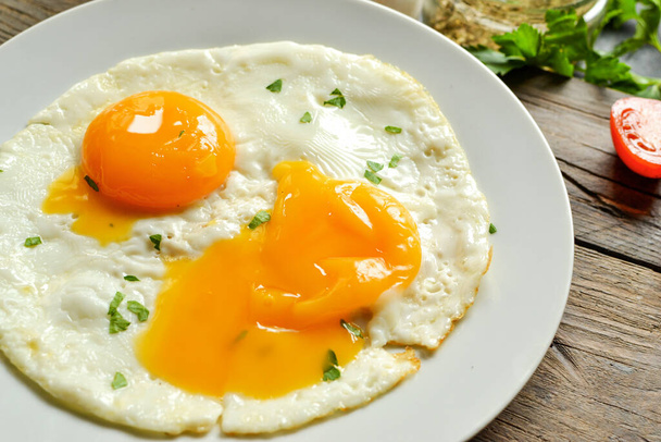 Жареные яйца в тарелке. Желток крупным планом. Вкусный завтрак. Аппетитный завтрак с яйцом
 - Фото, изображение