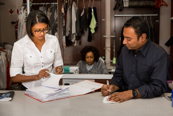 Johannesburg, South Africa - May 25, 2015: Small Business owners of local dry cleaning franchise reviewing data in file - Fotoğraf, Görsel