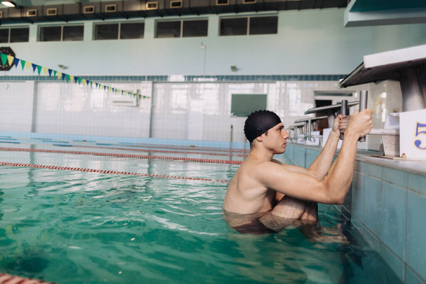 Instructeur de natation masculin en maillots de bain noirs et un bonnet de bain sort de l'eau
 - Photo, image