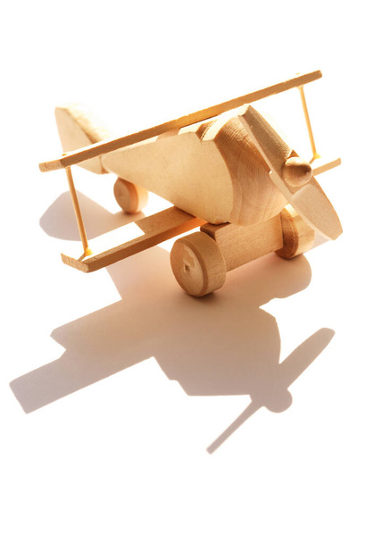 Travel concept. Small wooden airplane against sunlight with shadow - 写真・画像