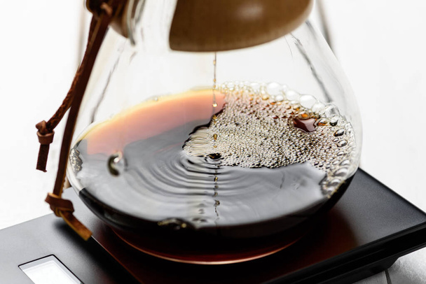 Koffie zetten met een filterdruppelaar. Koffie druipt door een papieren filter. Alternatieve manier om koffie te zetten. Macro close-up opname. - Foto, afbeelding