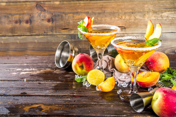 Refreshing summer drink, peach martini cocktails with gin or vodka and fresh peach garnish, wooden background copy space - Photo, Image