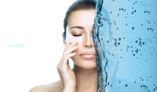 Moisturizing under eye patches concept. Beautiful model girl applying hydration eye patch. Beauty face, healthy clean skin. Spa eye skin care treatment. Portrait divided in half with blue water splash - Photo, Image