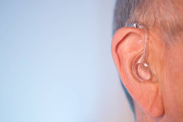 Кавказький білий літній чоловік у сучасному цифровому слуховому апараті на вусі з сірим волоссям.. - Фото, зображення