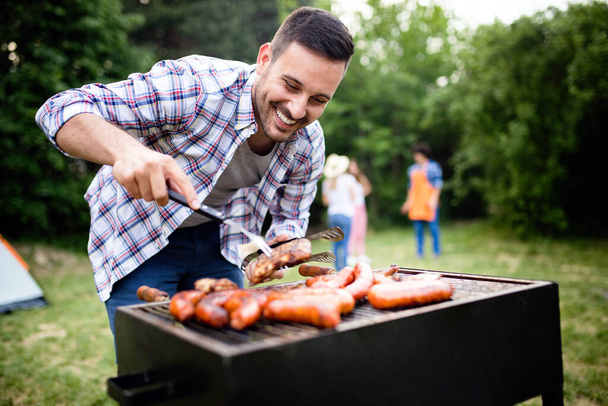 Handsome male preparing barbecue outdoors for friends - 写真・画像