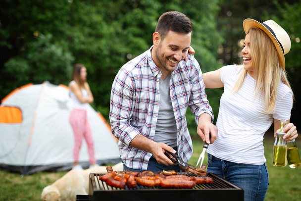 Young couple preparing sausages on a grill outdoors - Foto, Bild