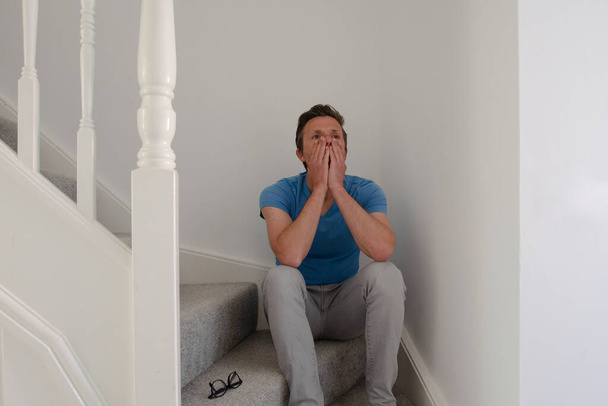 Homem sentado nas escadas olhando ansioso
 - Foto, Imagem
