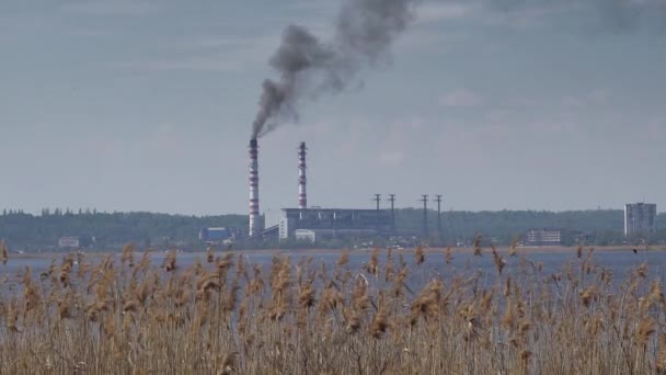 Rohre von Wärmekraftwerken liegen am Ufer des Flusses. Düstere Industrielandschaft - Filmmaterial, Video