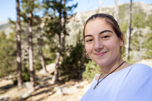 Young girl in T-shirt standing while smiling with the forest in the background - Photo, Image