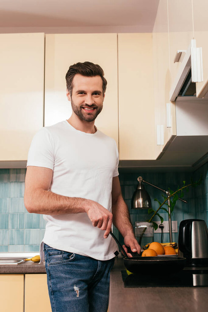 Bell'uomo che sorride alla telecamera mentre prepara la colazione in cucina
  - Foto, immagini