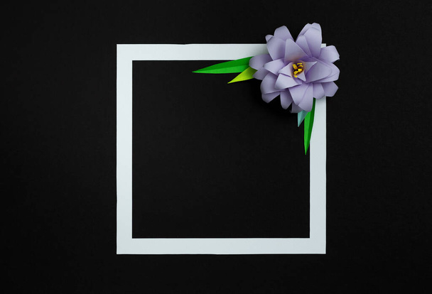 黒の背景にライラックパステルカラーの紙の花と正方形のフレーム。フラットレイアウト、コピースペース、花の芸術 - 写真・画像