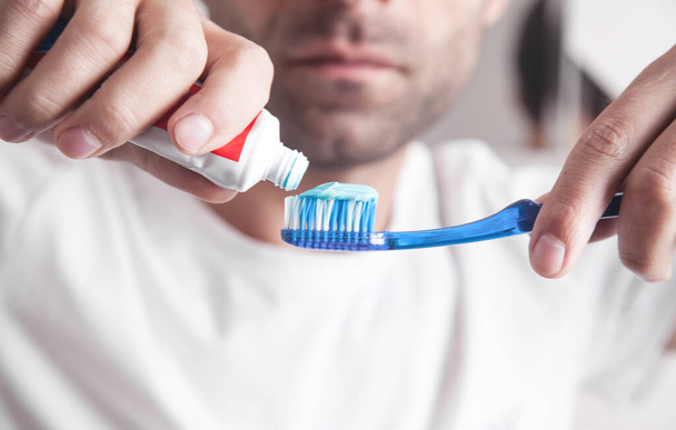Homme caucasien tenant brosse à dents et dentifrice dans la salle de bain
. - Photo, image