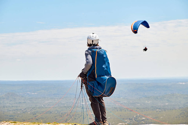 Закрытие человека со стропами его парашюта на холме, наблюдая полет на параплане, Кучи Корраль, Кордова, Аргентина, Южная Америка - Фото, изображение