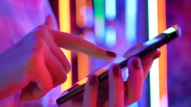 Nő használ okostelefon ellen fény színes háttér - közelkép oldalnézetben - Felvétel, videó