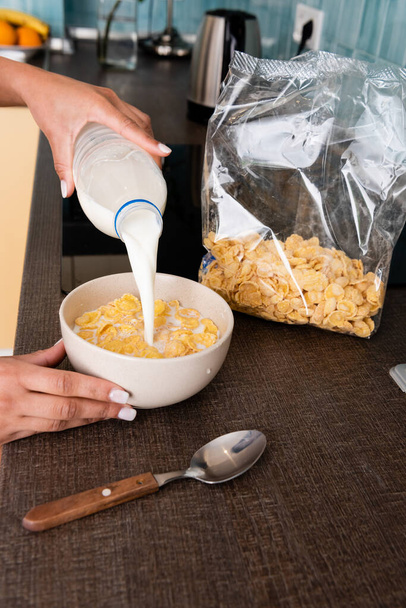 cropped view of african american woman pouring milk in bowl with cornflakes  - Foto, Bild