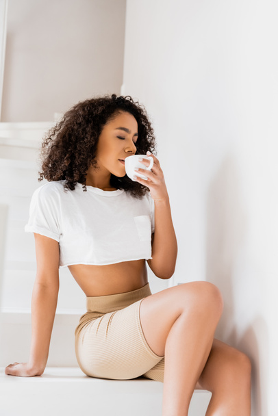 jovem afro-americana sentada nas escadas e bebendo café
 - Foto, Imagem
