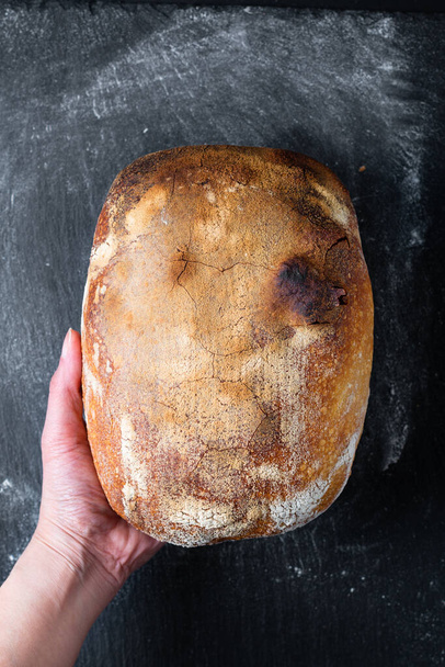 Tmavá nálada a tón Home Vaření Domácí bio rustikální Sourdough chleba na černém pozadí s kopírovacím prostorem - Fotografie, Obrázek