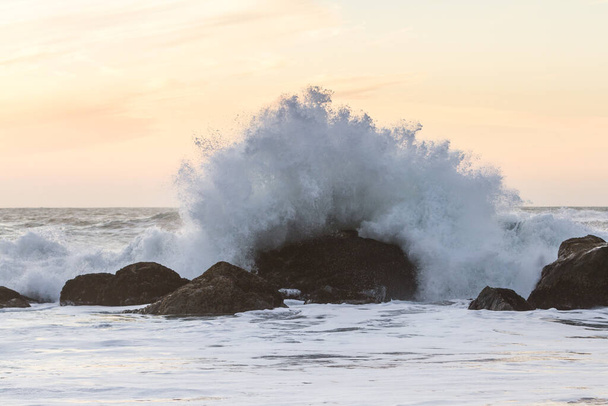 Rocky partvonal Nesika Beach, Oregon késő délután a nap közeledik a horizont és a hullámok ütköznek a sziklák - Fotó, kép