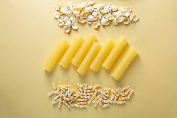 Overhead view of dry pasta on yellow background - Fotó, kép