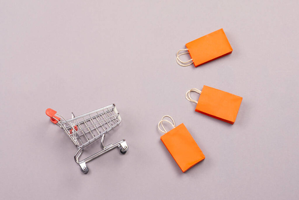 empty shopping basket with colorful shopping bags lay on grey background. shopping concept - Valokuva, kuva