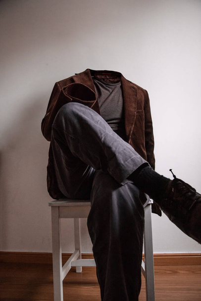 Uomo invisibile con vestito seduto su una sedia. Immagine verticale
. - Foto, immagini