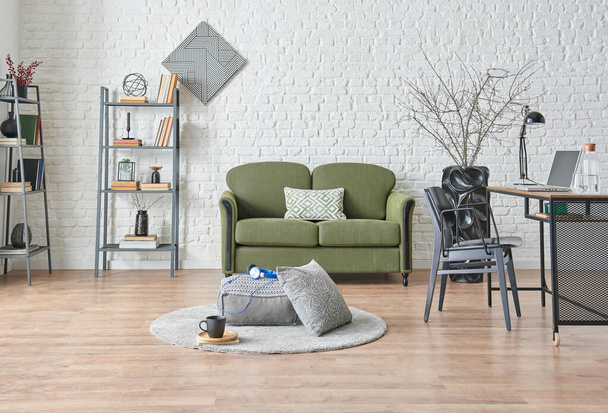 Fondo de pared de ladrillo blanco moderno, sofá verde y gris, detalle de muebles negros, mesa de trabajo con estante. - Foto, imagen