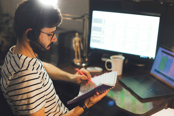 Homem barbudo elegante trabalha à noite no computador em casa durante a quarentena em auto-isolamento
 - Foto, Imagem